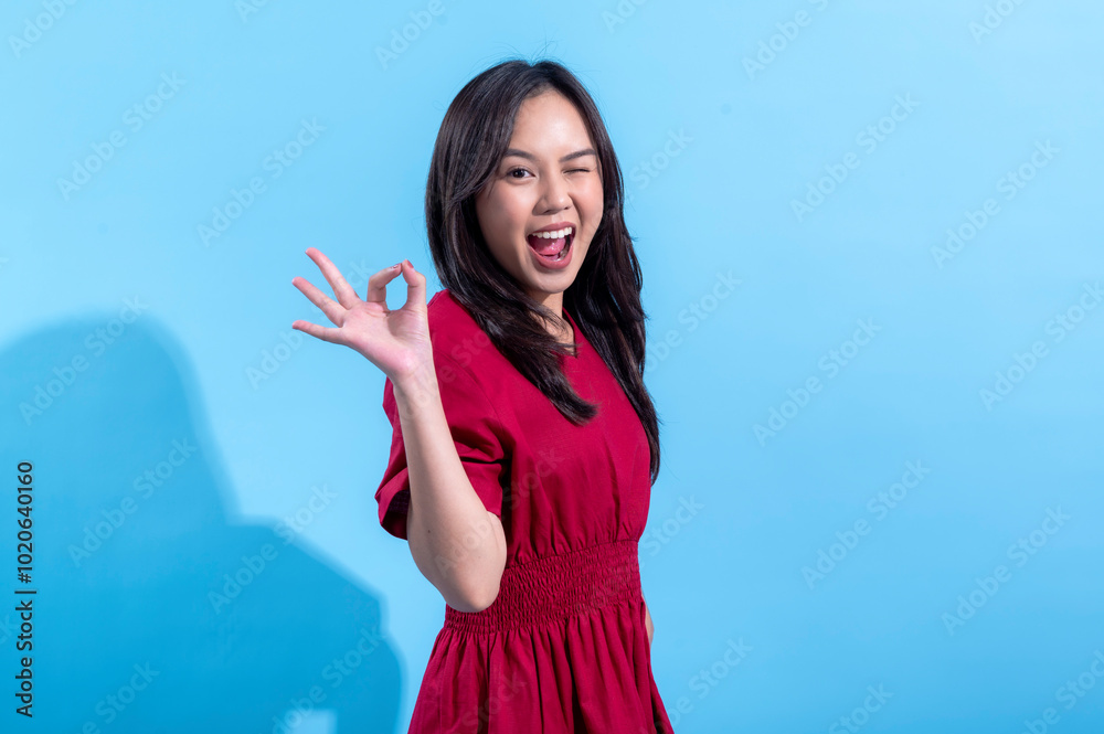 An Asian woman in a red dress smiling while making an An Asian woman in a red dress smiling while making an
