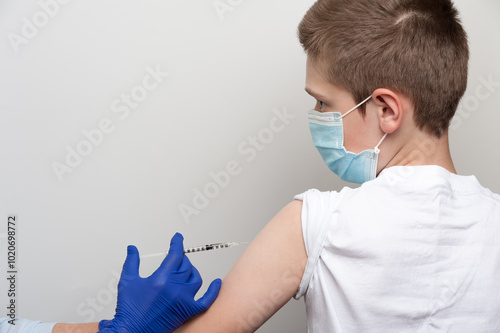 Medical and vaccination topic. Hands of nurse with syringe making vaccine injection to caucasian boy