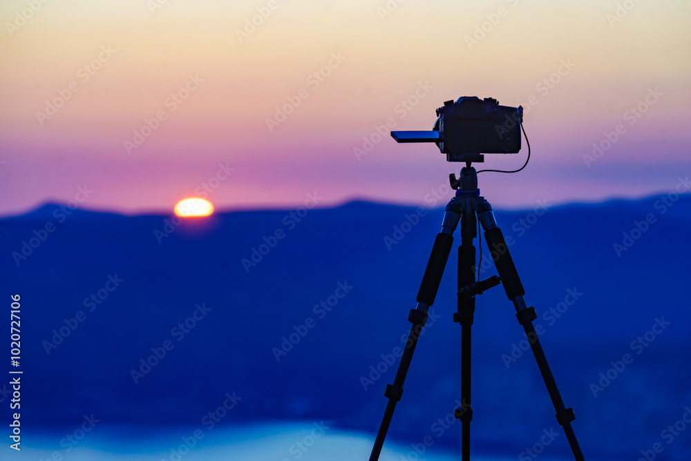 Camera on tripod taking picture of sunset over sea Camera on tripod taking picture of sunset over sea