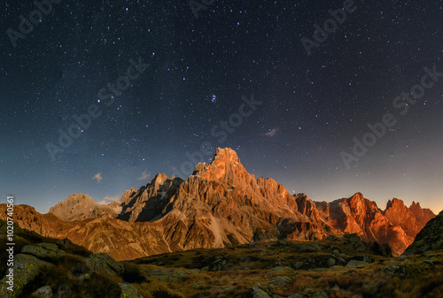 Cimon delle Pala mountain above Passo Rolle with clouds at night with stars
