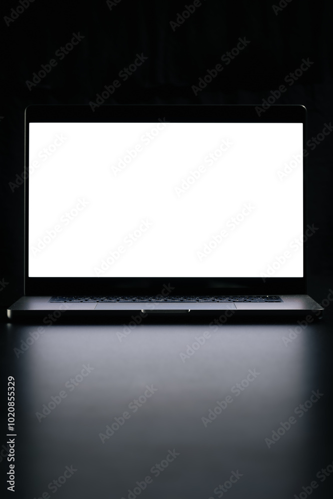 Fototapeta premium Modern laptop with blank white screen isolated on black background. Close up.