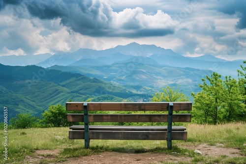 A wooden bench facing a vast, green mountain range under dramatic clouds, symbolizing a peaceful and serene view of nature.