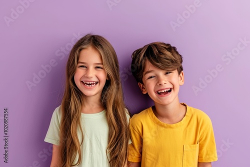 Portrait of two little children smiling and looking at camera against purple background