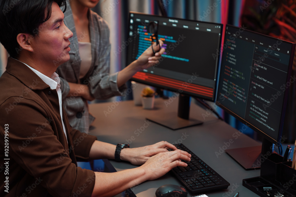 IT developers discussing with point to intelligent website development coder system running data online two screens information technology at neon light room at modern office. Infobahn.