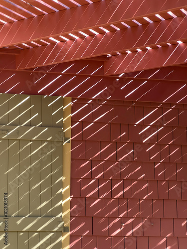 Transitory pattern of afternoon sunlight slanting across roof elements, gate, and shingled siding on exterior of a beach house in mid October on the Gulf Coast of Florida