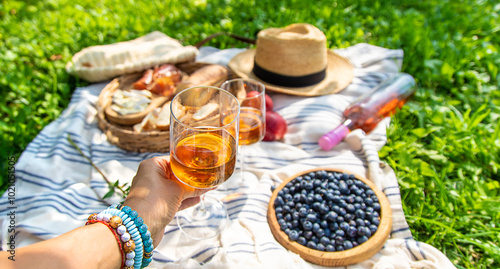 Wine in hands of woman at picnic. Selective focus.