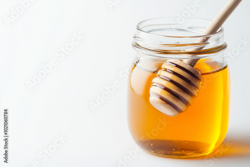 Jar of honey with wooden dipper, isolated on white background.