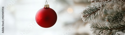 A vibrant red Christmas ornament hanging delicately from a pine branch, adding festive cheer to the holiday season.