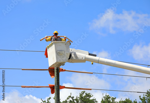Electrical contractor in a bucket truck insulates live power lines on old wooden poles. Soon to transfer the power lines to newly installed concrete poles to strengthen the grid in Fort Lauderdale, FL