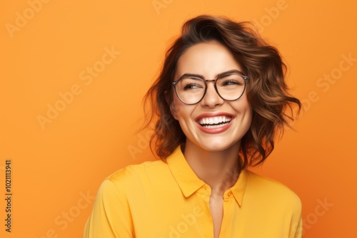 Portrait of happy smiling young woman in glasses, over yellow background
