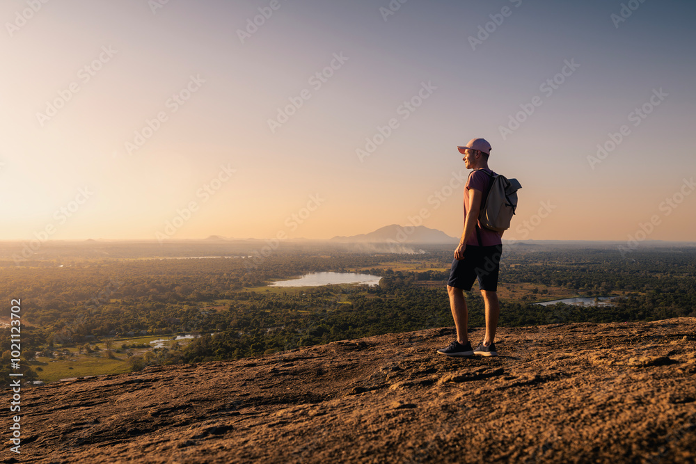 Man with backpack on top of rock looking at landscape at sunset. Beautiful scenery in Sri Lanka. . Man with backpack on top of rock looking at landscape at sunset. Beautiful scenery in Sri Lanka. .
