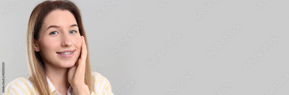 Beautiful woman with braces on light background. Banner design with space for text Beautiful woman with braces on light background. Banner design with space for text