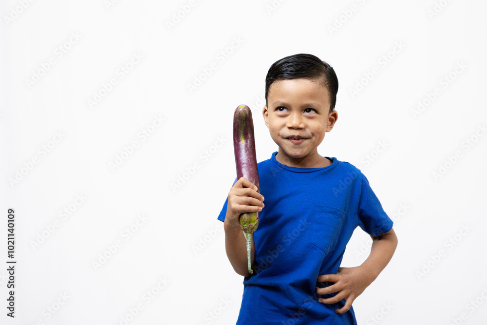 Cute and active Indonesian boy standing while posing with vegetables, healthy lifestyle concept, isolated white background.
