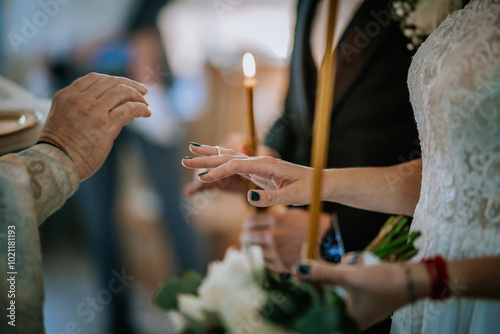 A close-up of a bride and officiant’s hands during a wedding ceremony, with the bride holding a candle, symbolizing unity and tradition..