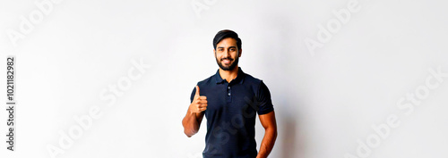 A South Asian man in a navy polo shirt giving a thumbs up against a white background.