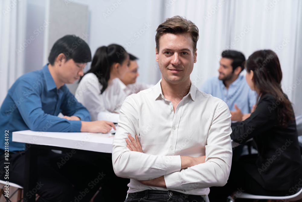 Confidence and happy smiling businessman portrait with background of his colleague and business team working in office. Office worker teamwork and positive workplace concept. Prudent Confidence and happy smiling businessman portrait with background of his colleague and business team working in office. Office worker teamwork and positive workplace concept. Prudent