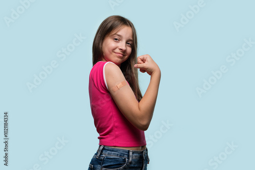 Young girl proudly flexing arm with bandage after vaccination