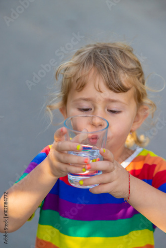 A child drinks water from a glass. Selective focus.