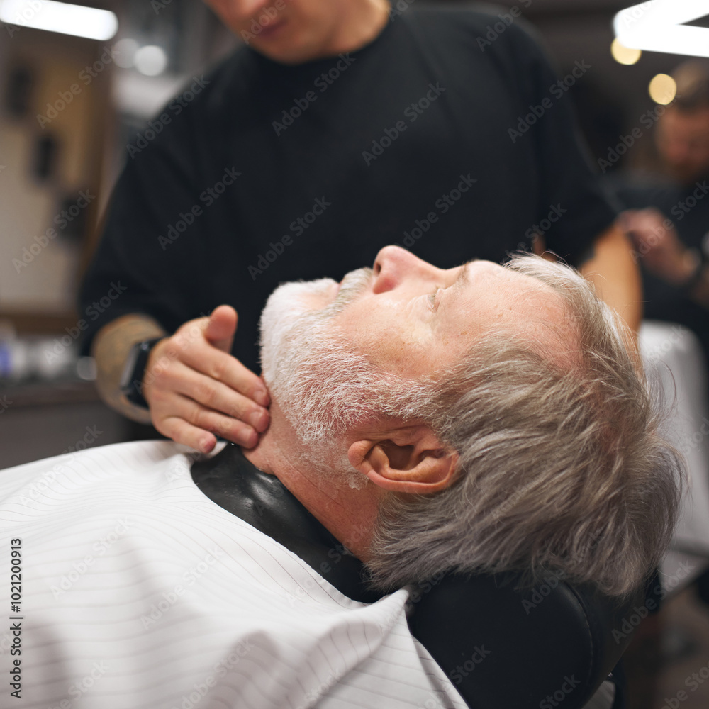 Obraz premium Elderly man visiting barber shop. Barber checking client neck area, ensuring smooth lines and clean shave. Detailed grooming. Concept of male beauty, barbershop, hairstyle, salon, hairdresser