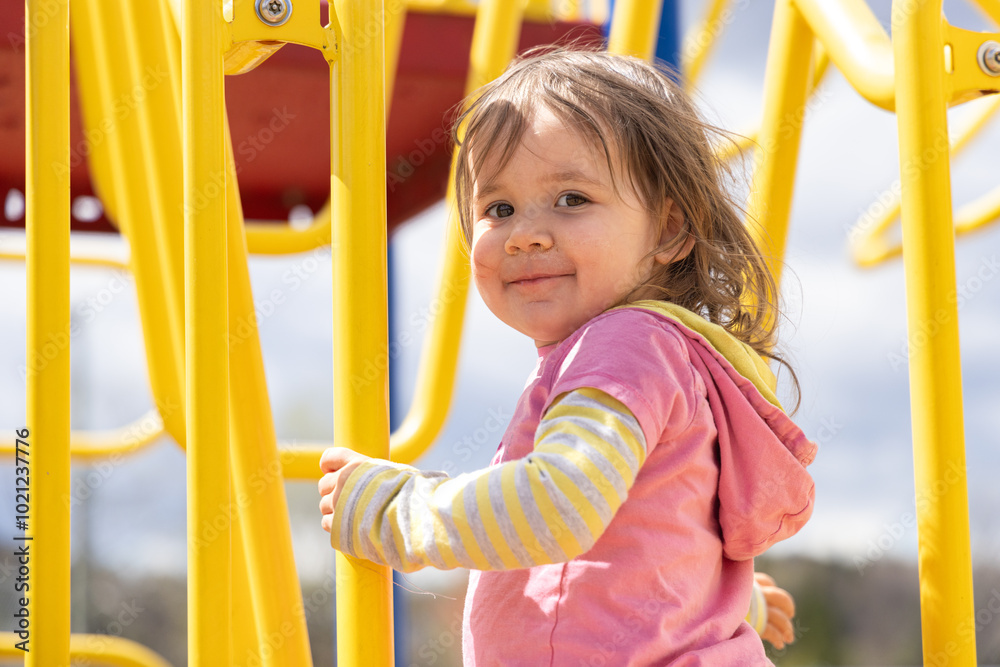 Girl playing happily on a colorful jungle gym at the park on a sunny day, full of energy and joy, exploring her imagination and having fun outdoors Girl playing happily on a colorful jungle gym at the park on a sunny day, full of energy and joy, exploring her imagination and having fun outdoors