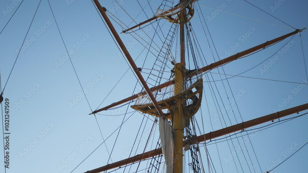 A large sailboat with a high mast and a yellow top. The sail is spread, the sky is clear. A large sailboat with a high mast and a yellow top. The sail is spread, the sky is clear.