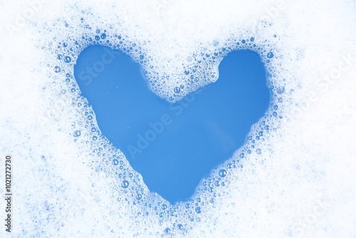 Heart shape made of detergent foam in water, top view. Hand washing laundry