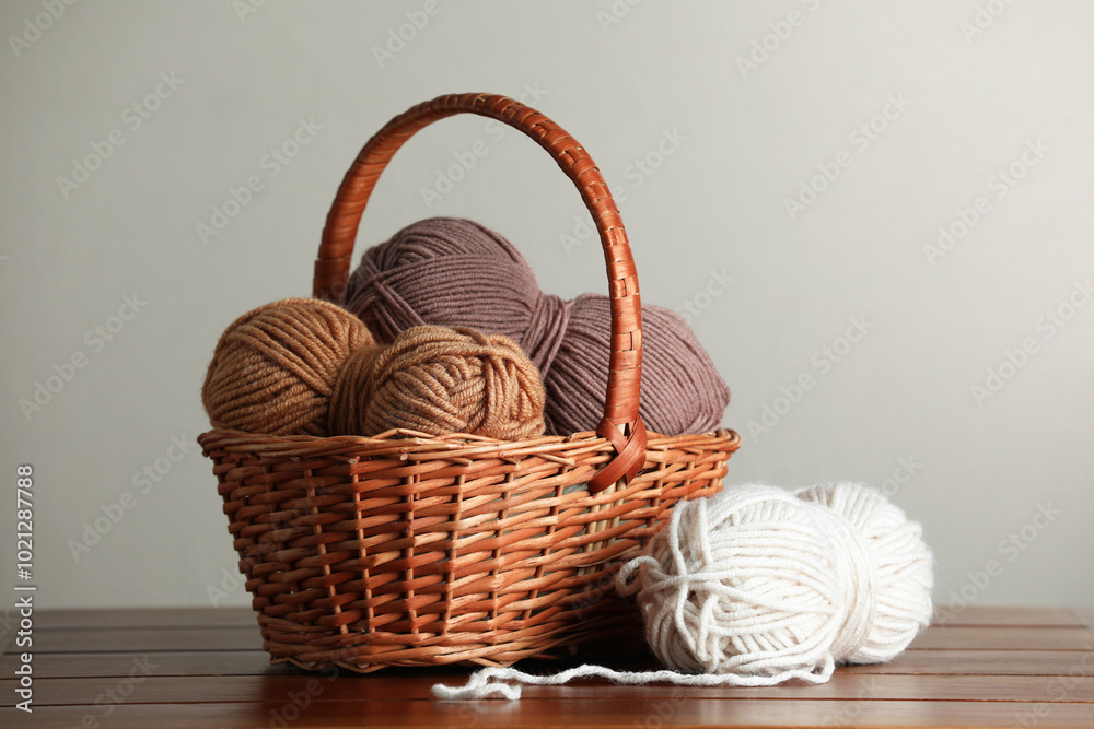 Knitting material. Wicker basket with skeins of soft yarn on wooden table Knitting material. Wicker basket with skeins of soft yarn on wooden table