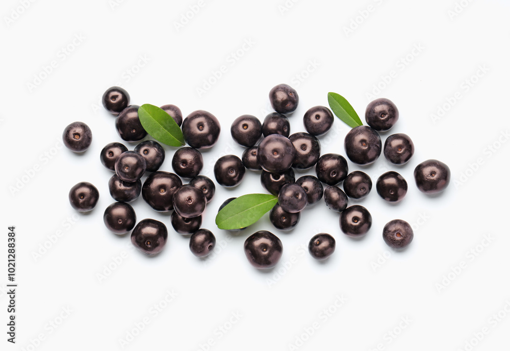 Ripe acai berries and leaves on white background, flat lay Ripe acai berries and leaves on white background, flat lay