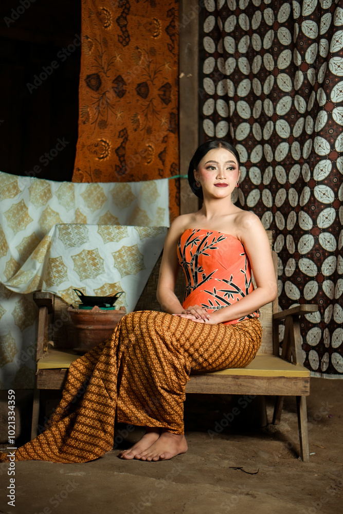 Fototapeta premium Young Indonesian women or fashion models wearing traditional Indonesian clothing or attire with batik motifs from Indonesian culture. Making or painting batik cloth. Making batik cloth.