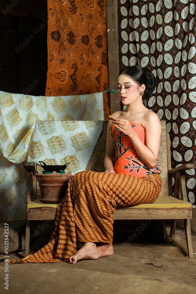 Fototapeta premium Young Indonesian women or fashion models wearing traditional Indonesian clothing or attire with batik motifs from Indonesian culture. Making or painting batik cloth. Making batik cloth.