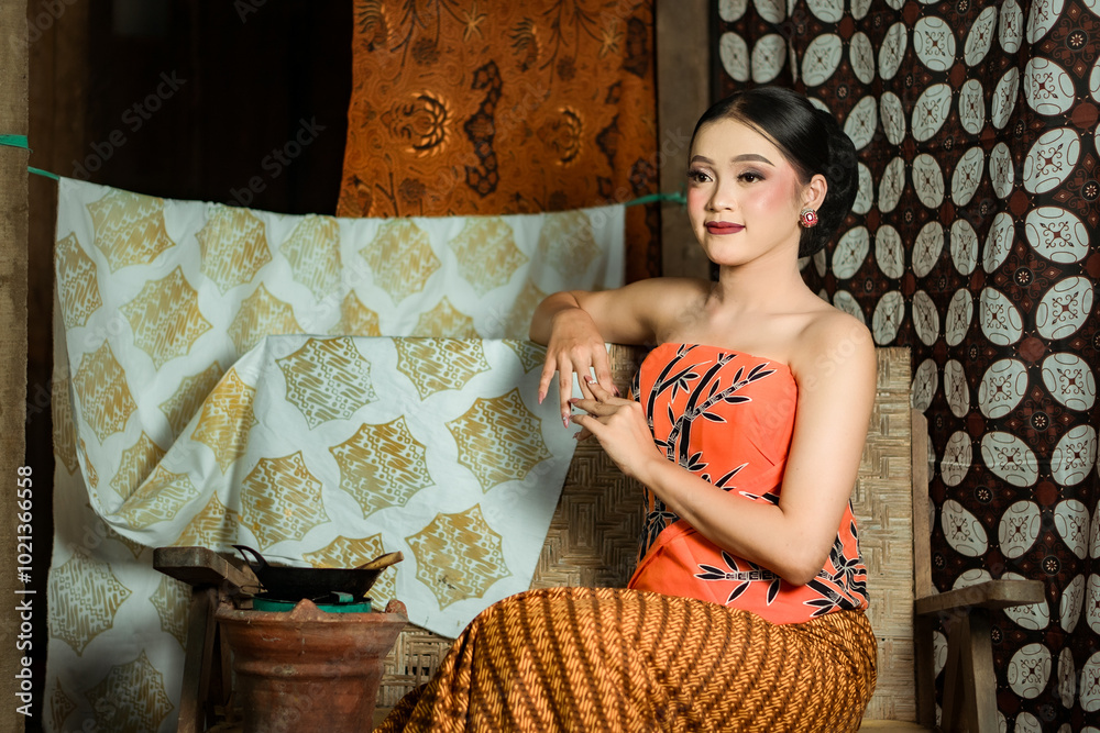 Fototapeta premium Young Indonesian women or fashion models wearing traditional Indonesian clothing or attire with batik motifs from Indonesian culture. Making or painting batik cloth. Making batik cloth.