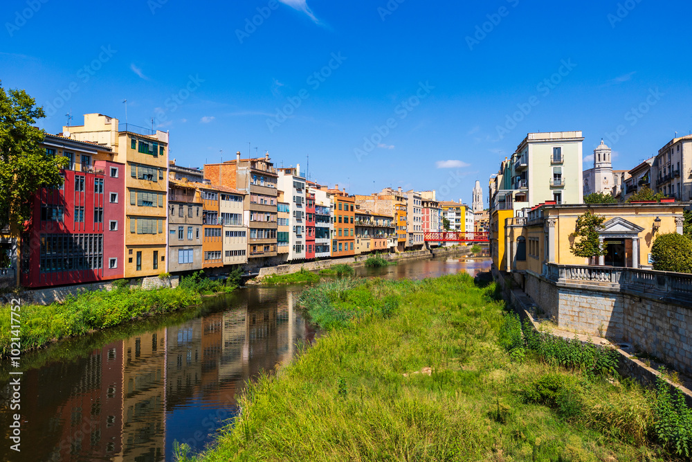 Fototapeta premium Clocher de style gothique de la Basílica Sant Feliu de Gérone dominant le Riu Onyar et ses immeubles colorés