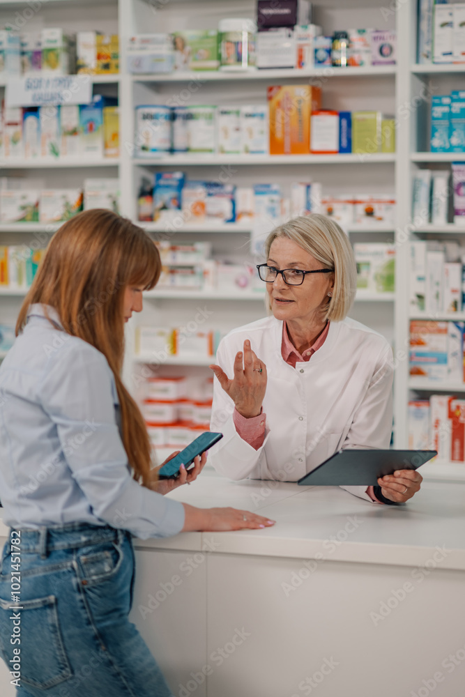Senior druggist with tablet having consultations with client at drugstore Senior druggist with tablet having consultations with client at drugstore