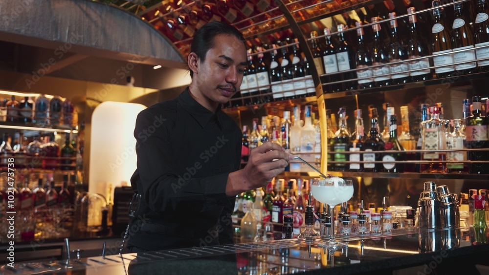 Asian bartender serving mixed creamy vodka cocktail glass adding pink flower top with sugar burned on ice at front making special drink, focusing alcohol refreshing at luxurious counter bar. Vinosity. Asian bartender serving mixed creamy vodka cocktail glass adding pink flower top with sugar burned on ice at front making special drink, focusing alcohol refreshing at luxurious counter bar. Vinosity.