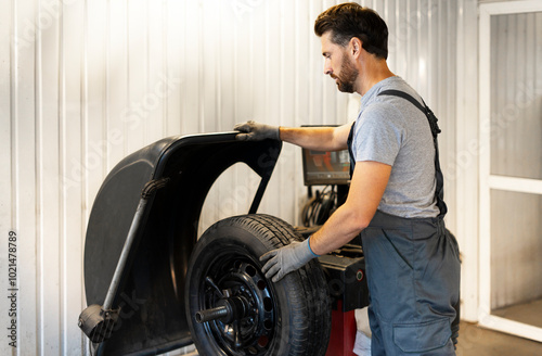 Φωτογραφία Mechanic mounting a tire on a balancing machine in a workshop
