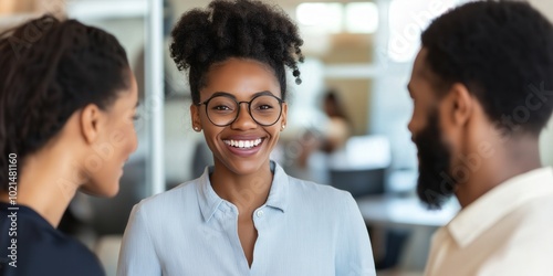 Young smiling businesspeople standing in a modern office discussing successful deals or work projects