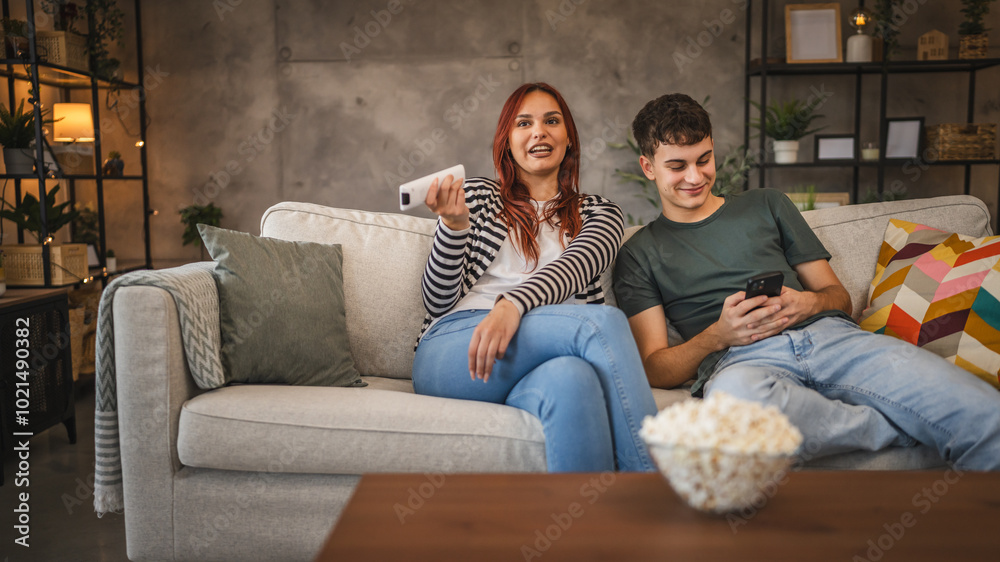 Young couple girlfriend watch movie while boyfriend use cellphone