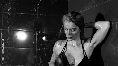 Fotografie Sexy woman fashion model takes a shower in a swimsuit, posing for the camera