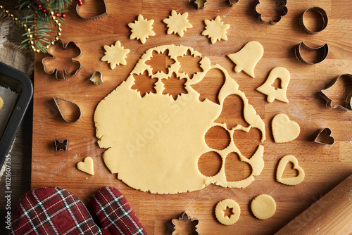 Rolled out pastry dough with cut out shapes on a wooden board - preparation of homemade Linzer cookies