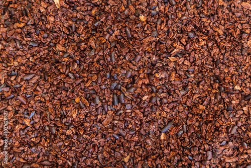 Lot of crushed cocoa beans forming a background, waiting to be processed by a chocolatier. Selective focus