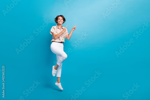 Full length photo of cheerful nice girl wear trendy clothes presents mockup novelty empty space isolated on blue color background