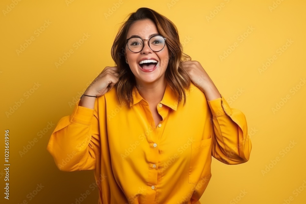 Portrait of a happy young woman with glasses over yellow background.