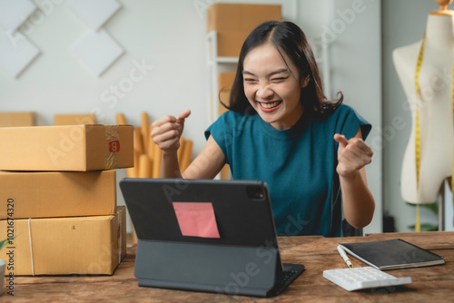 Asian sme business owner is celebrating a business success while looking at her tablet