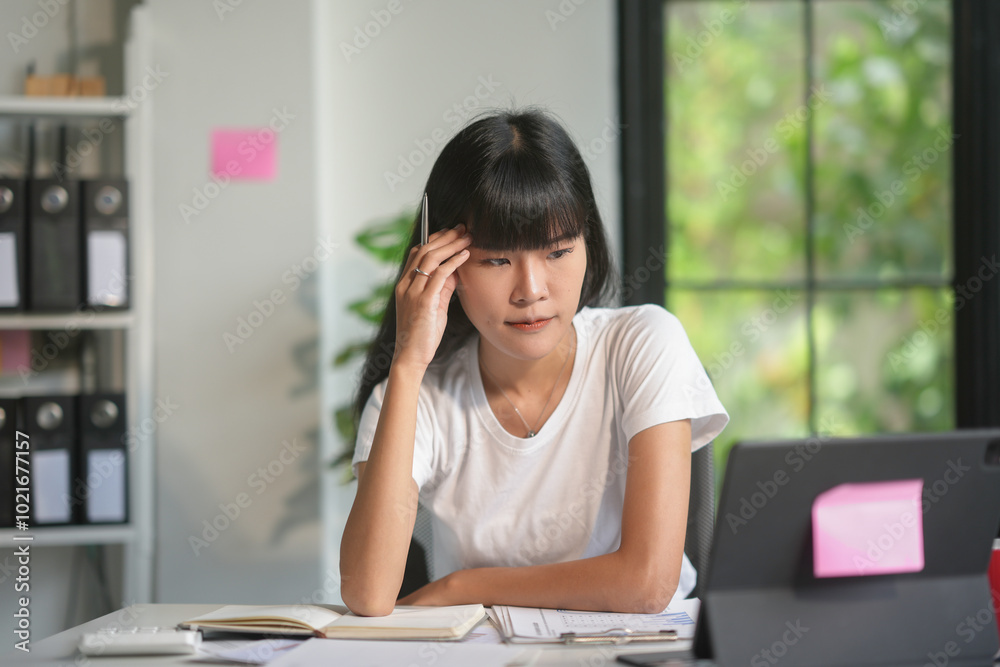 Asian accountant woman is feeling stressed and having a headache while working on laptop at office Asian accountant woman is feeling stressed and having a headache while working on laptop at office
