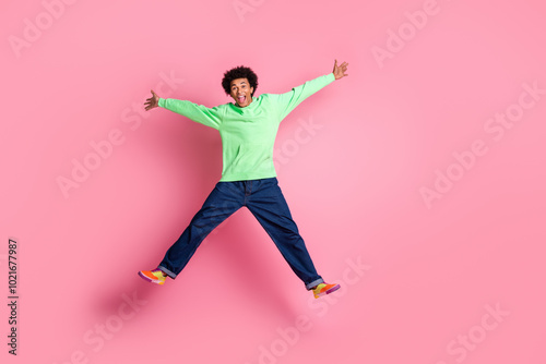Full size photo of nice young man jump empty space wear green hoodie isolated on pink color background
