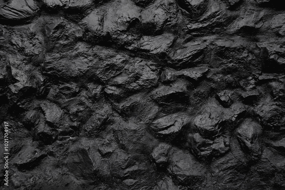 Fototapeta premium Black embossed stone wall for abstract background and texture for interior or exterior design. Beautiful patterns, space for work, banner, wallpaper close up.
