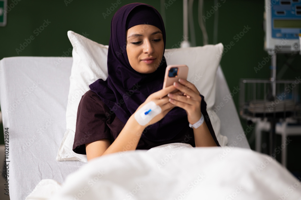 Arab girl patient in a hospital room, chatting with loved ones on her mobile phone.