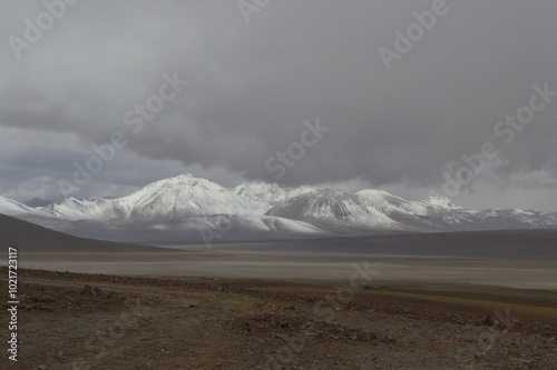 Dia nublado no deserto da Bolívia e montanhas com neve ao fundo photo