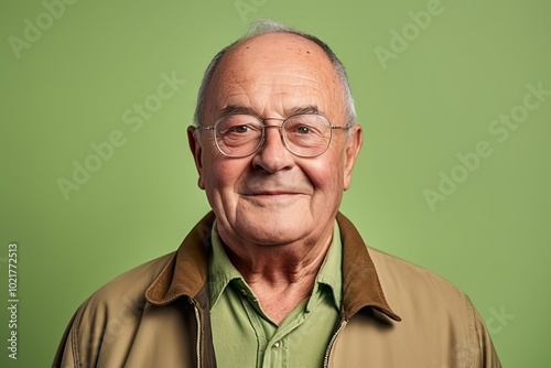 Portrait of a happy senior man with glasses against a green background