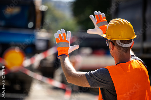 Construction worker directing traffic near work zone during bright sunny day, ensuring safety on busy road